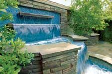 The Canvas:Small grassy lot, a vacant wall, a need for rejuvenationThe Palette: The strength of Pennsylvania stone, the beauty of blue Venetian glass, the warmth of an outdoor fireplaceThe Masterpiece:Three shimmering falls, two gracious curves, one voluptuous package