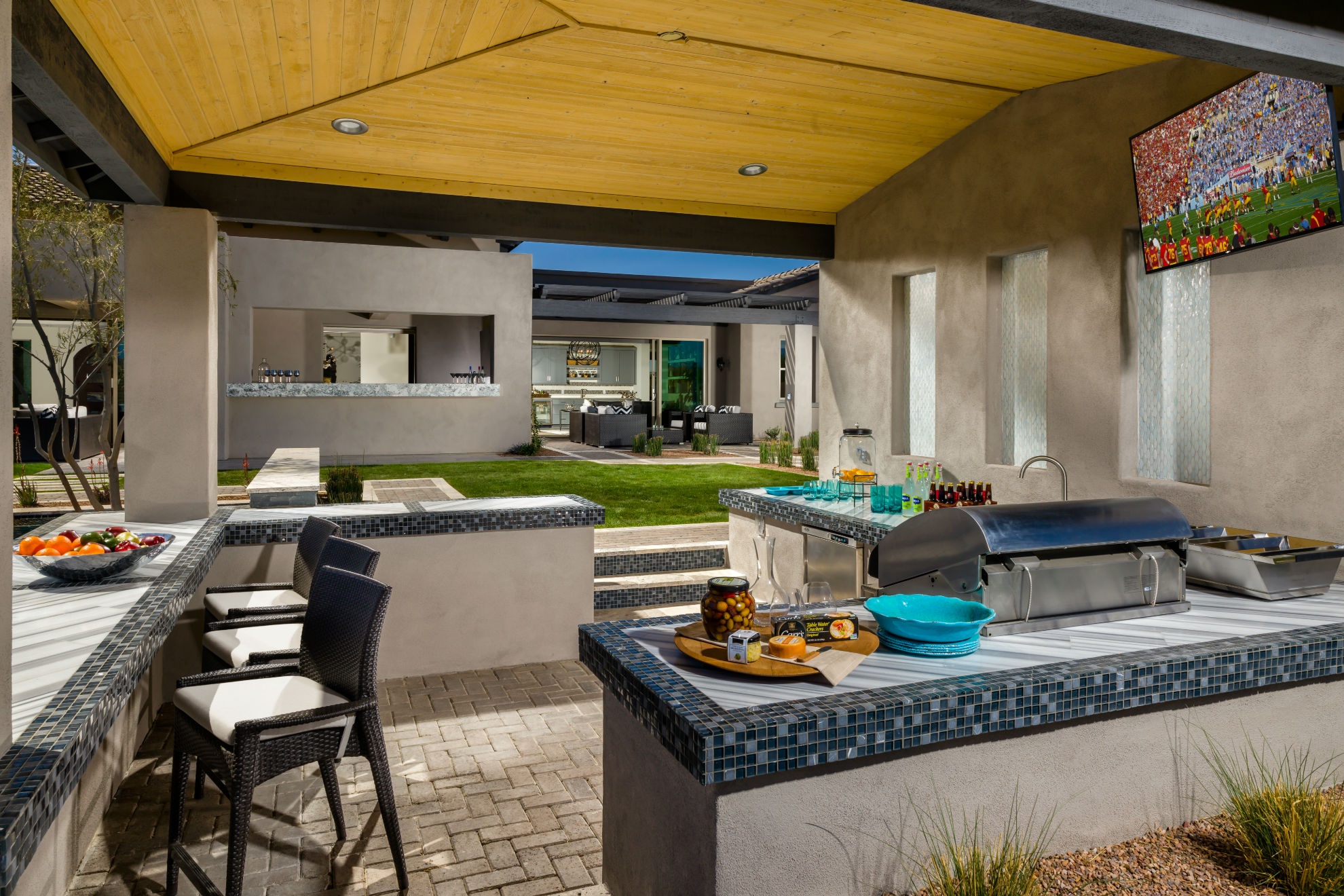 One of the two outdoor kitchens on the property that come complete with all the essentials, this pass through space features everything from ample seating and a tv to a grill and lighting for evening gatherings.