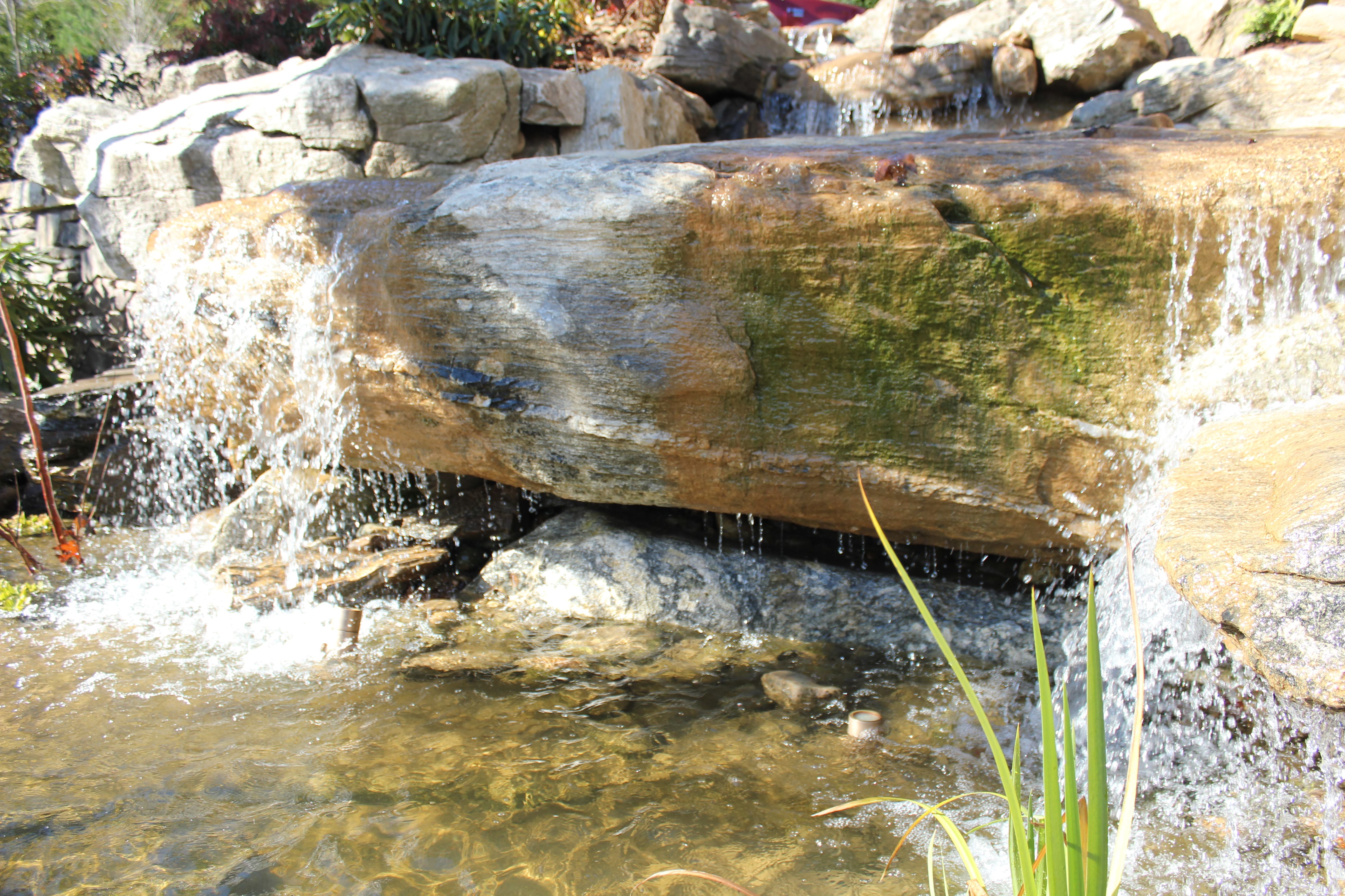A flat stone chosen to create a wide fall. Some of these larger specimens were cut to fit against the walls of the concrete basin.