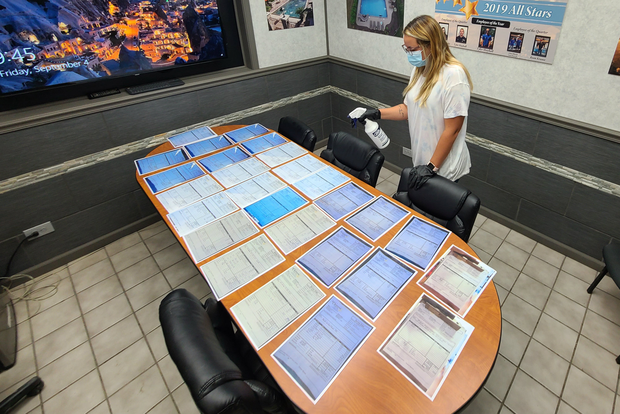 An employee with All Seasons Pools & Spas in Orland Park, Ill., disinfects documents so they can safely change hands from field crews to the office staff.