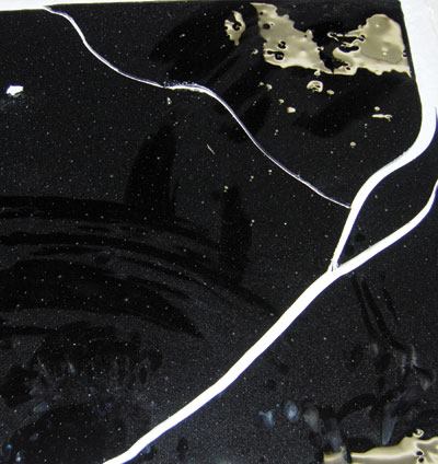 These tiles show cracks and stresses purposely induced in a manufacturer’s lab for testing. The black glass shows internal stress caused by the incorporation of incompatible raw materials. In the green tile, a thermal-shock crack developed when staff brought the tile to a high temperature, then soaked it in cold water. On an actual installation, these cracks generally are clean and run all the way through the tile. The purple glass has experienced a strain during annealing, a process by which cooling is controlled. Each glass formula has its own annealing point, which must be observed to avoid these stresses.