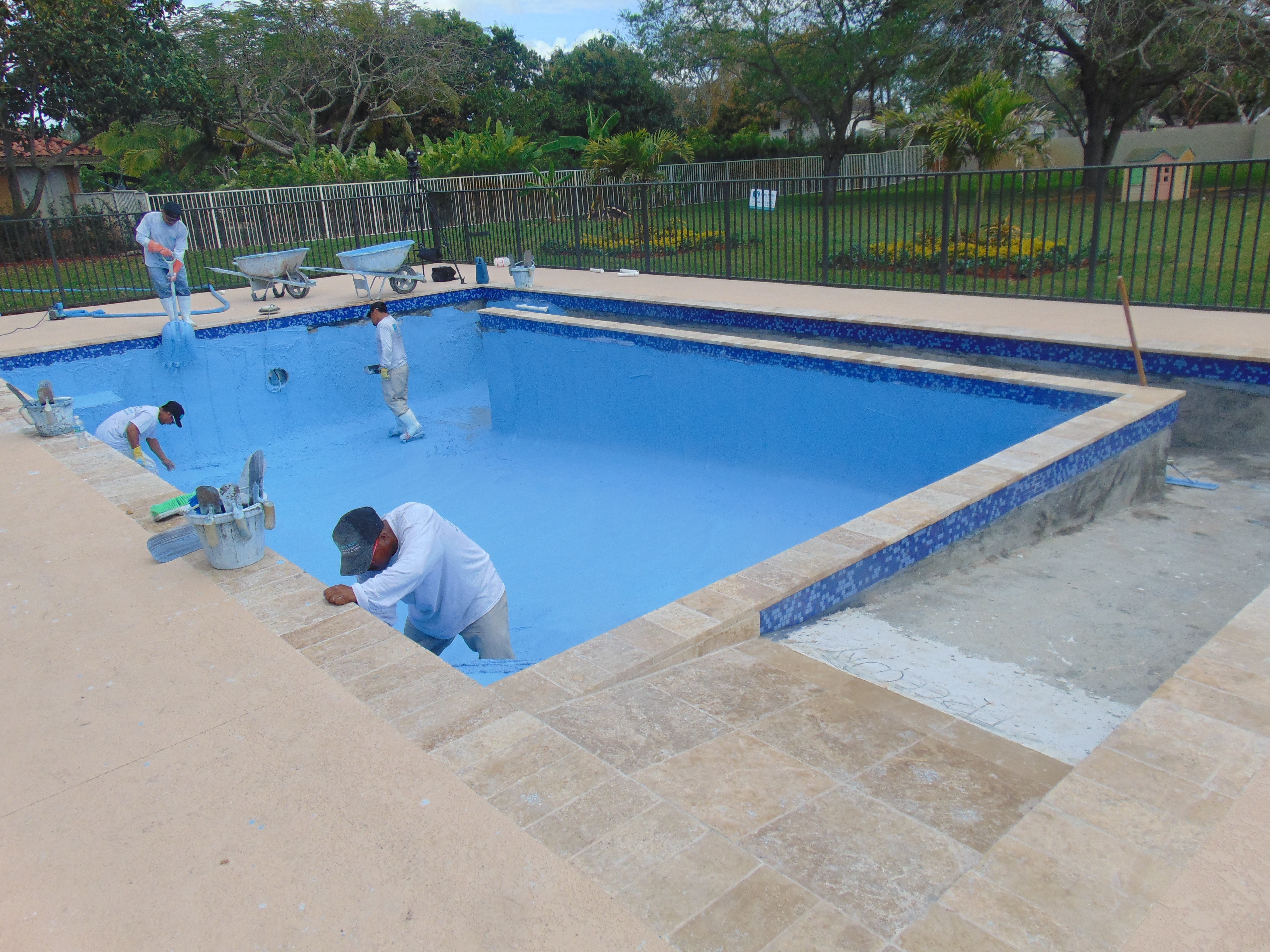 Workers install the plaster to the pool.