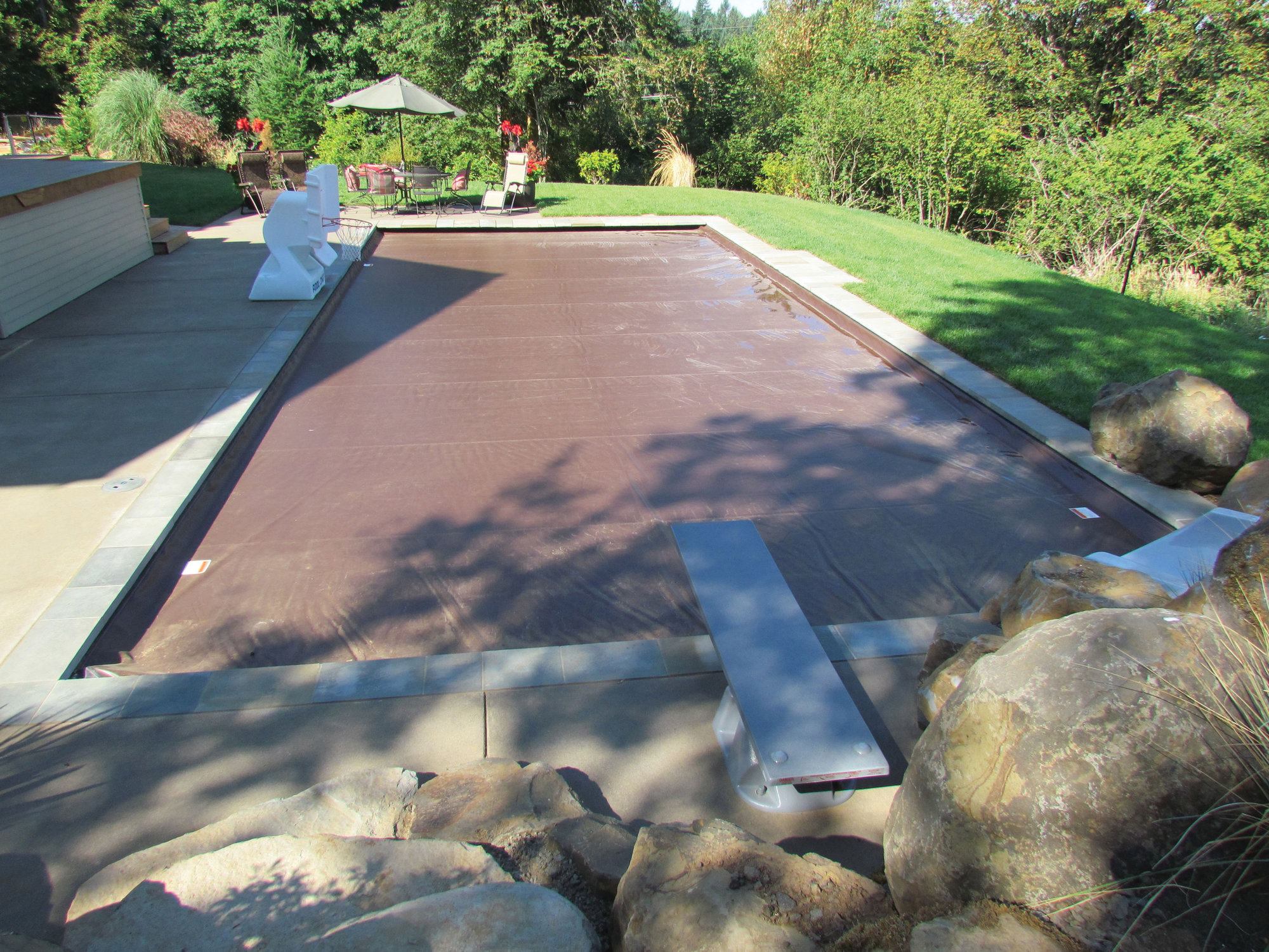 Dealing with the elements: Despite features such as a slide, diving board and water basketball hoop, this 20-by-40-foot residential pool built by Neptune Swimming Pool Co. of Clackamas, Ore., covers up nicely. 