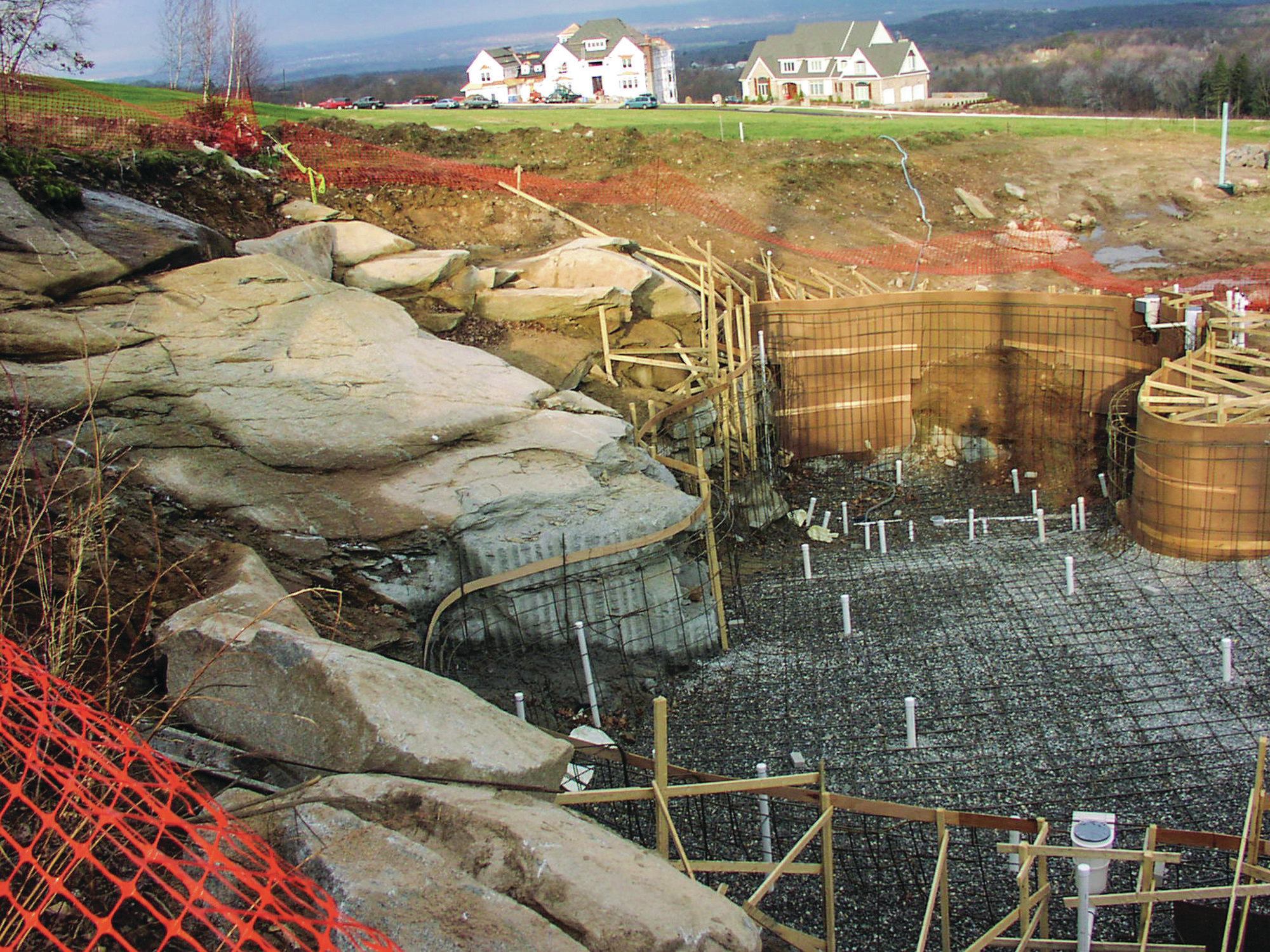 After exposing the stable ledge and moving loose material out of the way, Aqua Pool construction supervisor Gregg Pruitt worked closely with the blasting contractor to define the edge of the pool. This involved drilling and blasting a vertical wall out of the solid granite — to a depth of 10 feet at the deep end of the 8-foot pool. “During this part of the job we were continually on site with the homeowner and the blaster to create the final shape of the pool,” says Giannamore. The company’s gunite crew were then able to form and shoot the concrete walls. “We didn’t pin to the ledge, but we placed the walls so it looks like the rock formations are connected to the pool, even though they’re not,” Giannamore adds. “We set rocks between the ledge and the pool, grouted and waterproofed, so that as water came down these rocks it would fall into the pool.”  

The pool features an in-floor cleaning system and touchscreen controller.