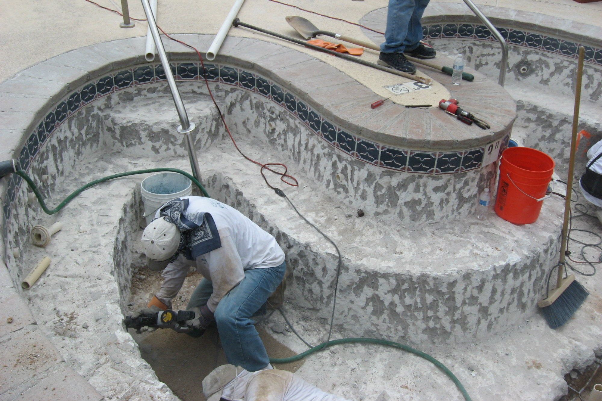 Some chipping must be performed around the tile lines and fittings to prepare for a bond coat. Less powerful equipment is used on walls.