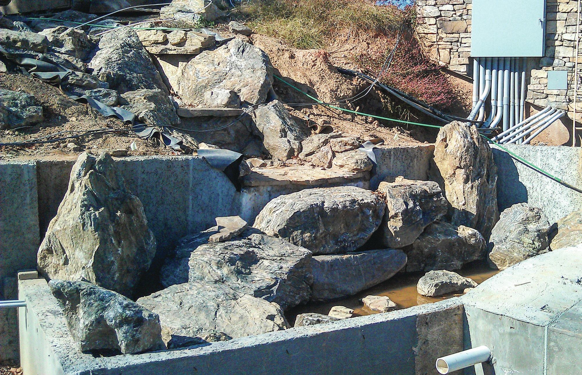 Building the waterfall: The original contractor on the stream had planned to use a rubber liner, but Dorsey wanted to minimize chances of leakage and failure. Considering the property was on a hillside and the backyard shored up with a 16-foot-high retaining wall, damage and costs to repair could be catastrophic. “They’d just spent about $250,000 on a retaining wall just to create a site for the pool,” Dorsey says. “So we can’t have a failure. Also, we needed something to support the weight of some large stones.” For durability, he and his crews built a 19-foot-long concrete shell to capture water from the final drop. The basin’s back wall is buried about 8 feet deep.