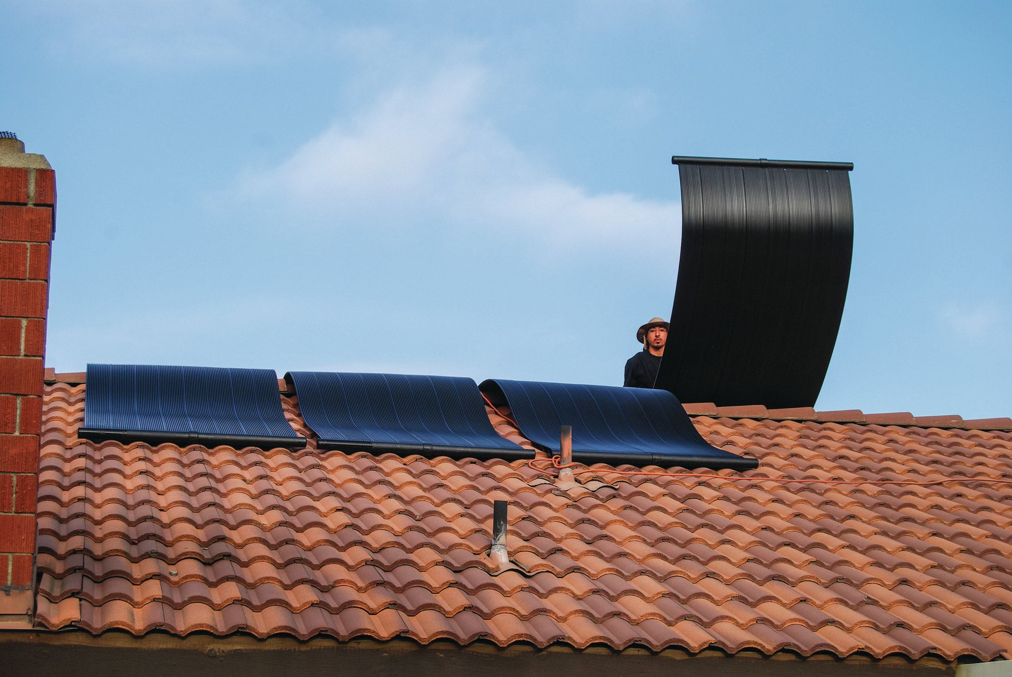 1) Place the solar collectors on a south-facing roof. There won’t always be a way to make the collectors face directly south, but ensure they get as much sun exposure as possible. The collectors are flexible and the number used depends on the size of the pool to be heated. This installation had six collectors, while those with bigger pools might require nine or 10.